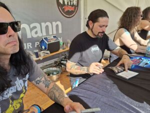 Ronnie Romero verewigt sich bei den Fans per Autogramm. Links Gitarrist Gus G.